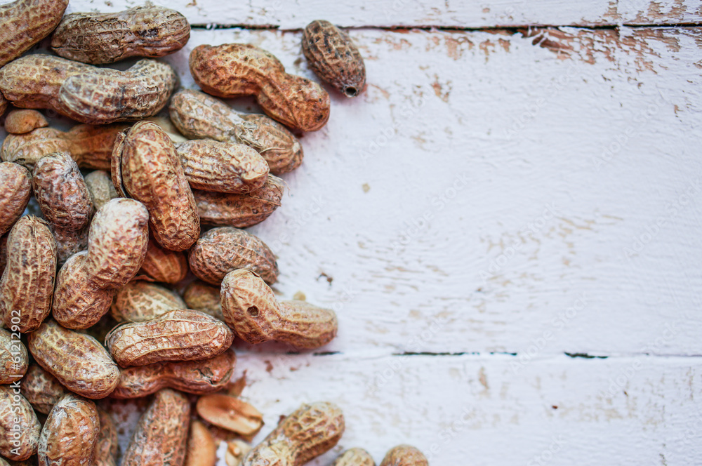 Fototapeta premium Roasted peanuts on white wooden background
