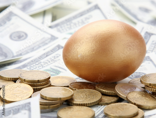 A gold egg lying on dollars and coins photo