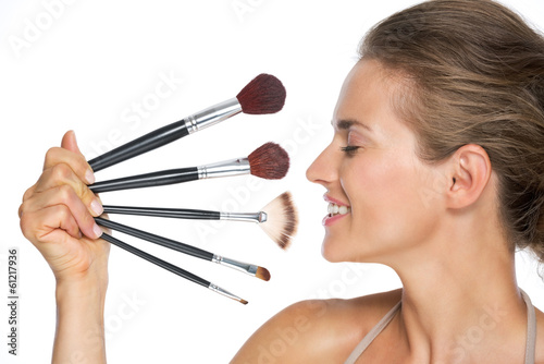 Profile portrait of happy young woman with makeup brushes
