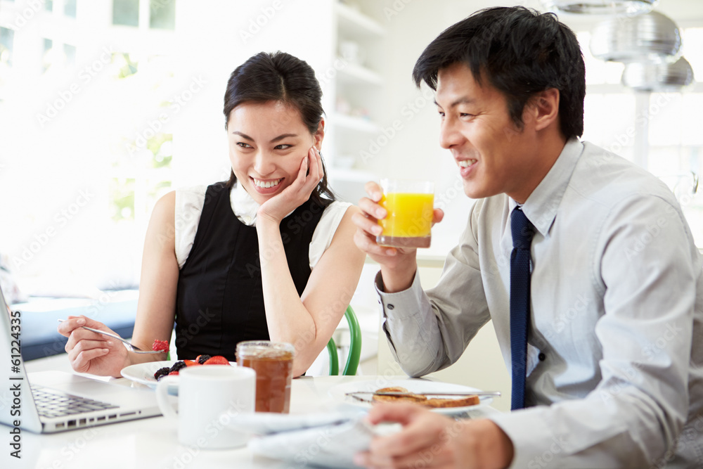 Asian Couple Looking at Laptop Over Breakfast Asian Couple Looking at Laptop Over Breakfast