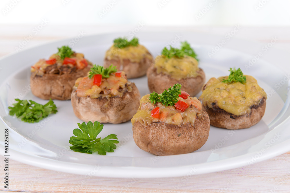 Stuffed mushrooms on plate on table on light background Stuffed mushrooms on plate on table on light background
