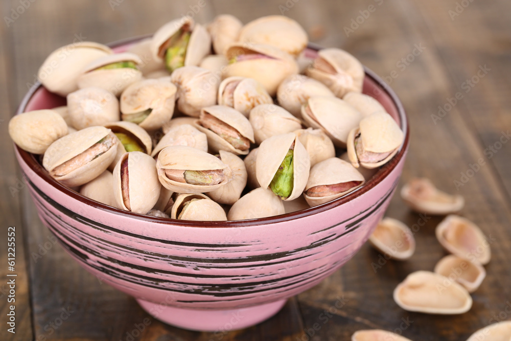 Pistachio nuts in bowl on wooden background Pistachio nuts in bowl on wooden background