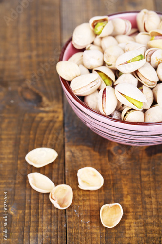 Pistachio nuts in bowl on wooden background