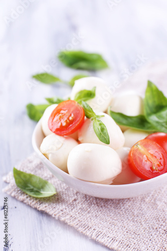 Tasty mozzarella cheese with basil and tomatoes in bowl,