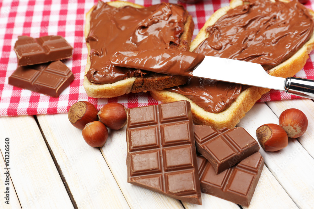 Bread with sweet chocolate hazelnut spread on wooden background Bread with sweet chocolate hazelnut spread on wooden background