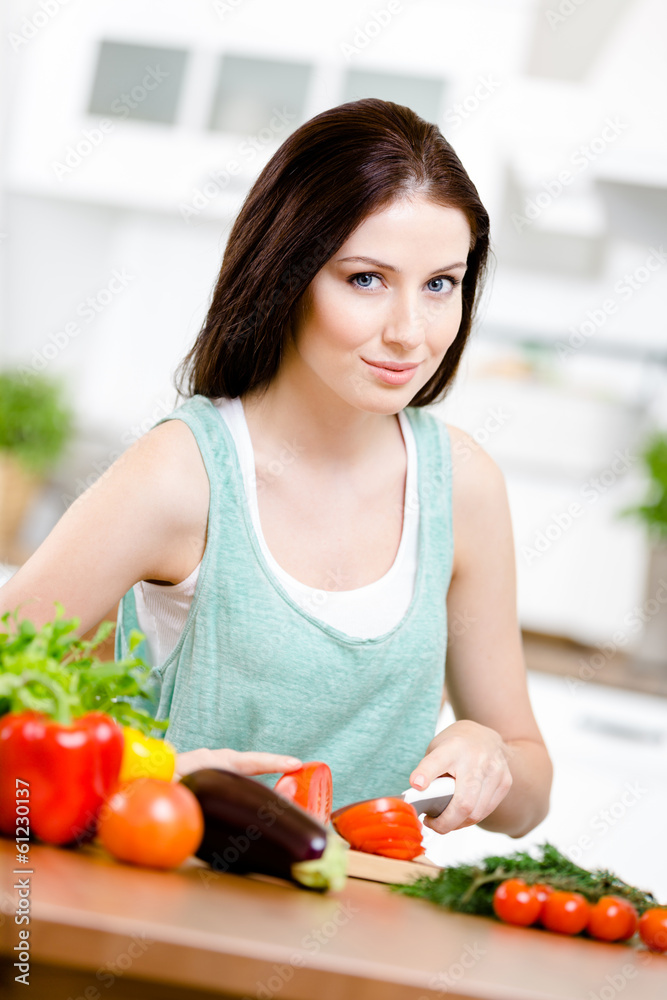 Girl slices vegetables for salad sitting at the kitchen Girl slices vegetables for salad sitting at the kitchen
