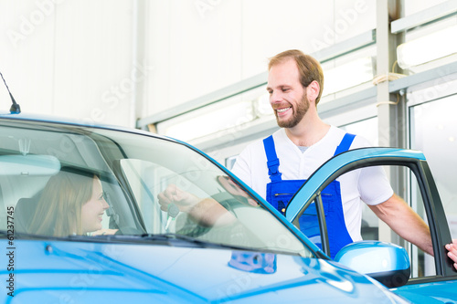 Kundin und Mechaniker an Auto in Werkstatt