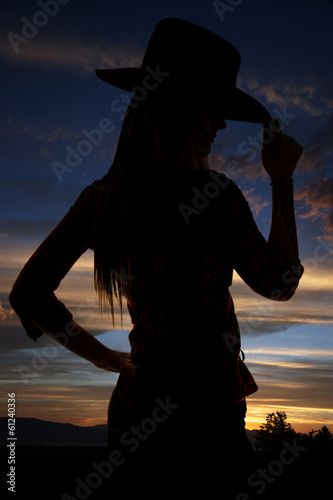 silhouette of cowgirl tipping her hat at sunset photo