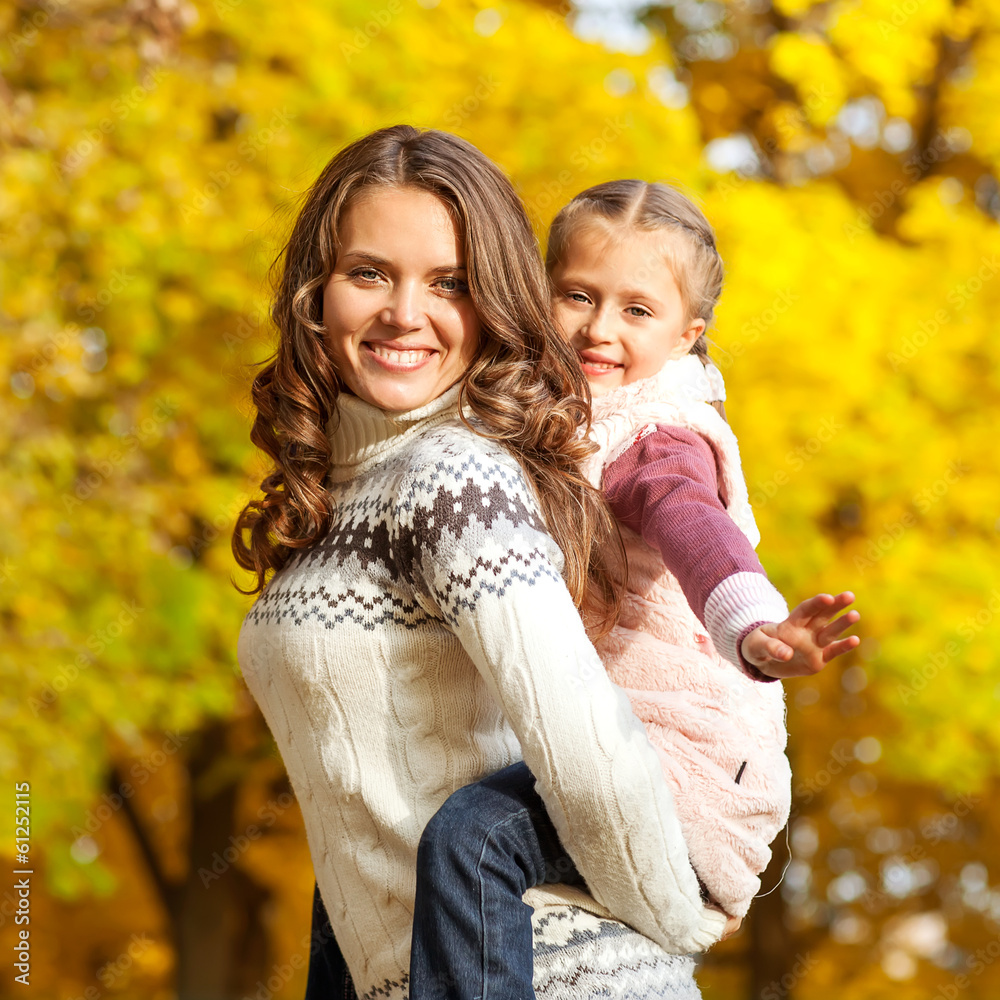 Young mother and her toddler girl have fun in autumn