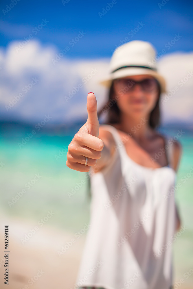 Young beautiful woman showing thumbs up on the beach