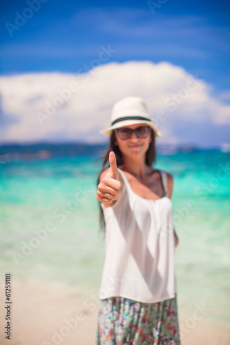 Young adorable woman showing thumbs up on white beach © travnikovstudio