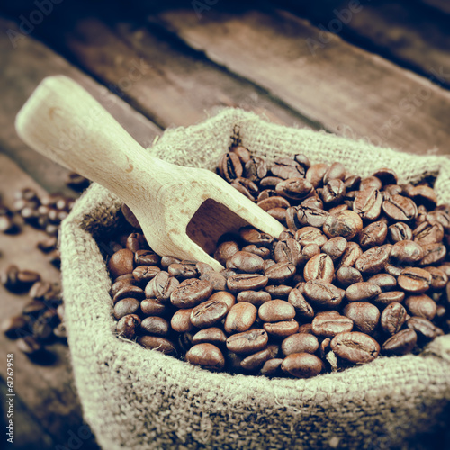 Vintage stylized photo of sack with coffee beans and wooden scoo photo