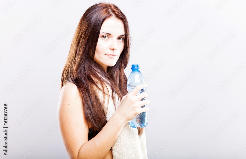 Young woman after fitness with towel and water bottle Young woman after fitness with towel and water bottle