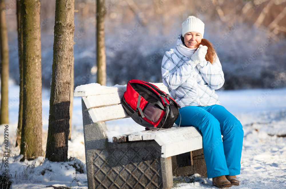 Frozen young woman with backpack on park bench at winter season Frozen young woman with backpack on park bench at winter season