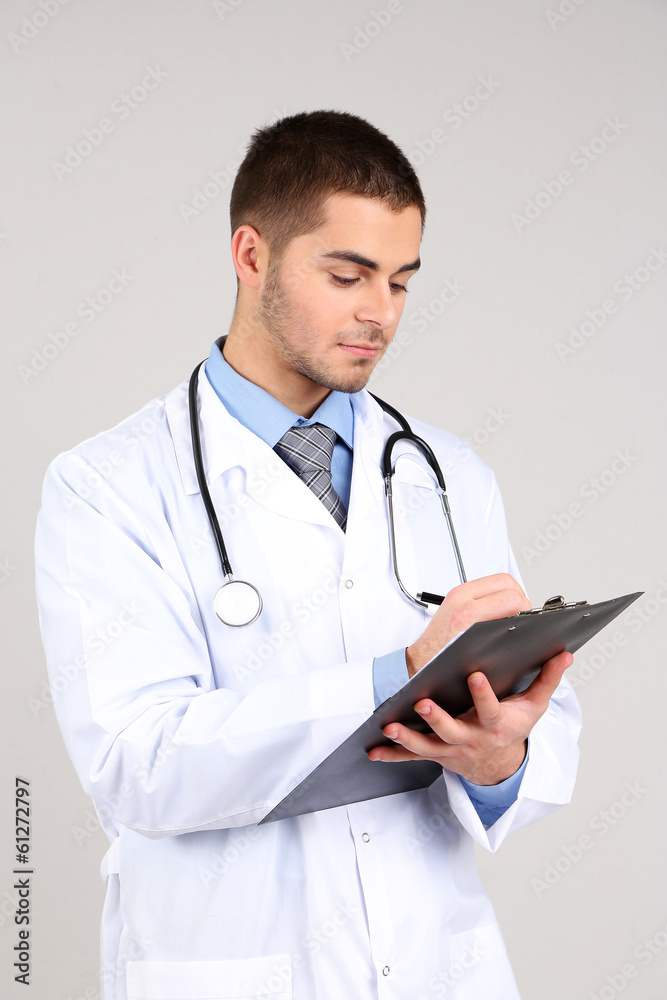 Male Doctor standing with folder, on gray background Male Doctor standing with folder, on gray background