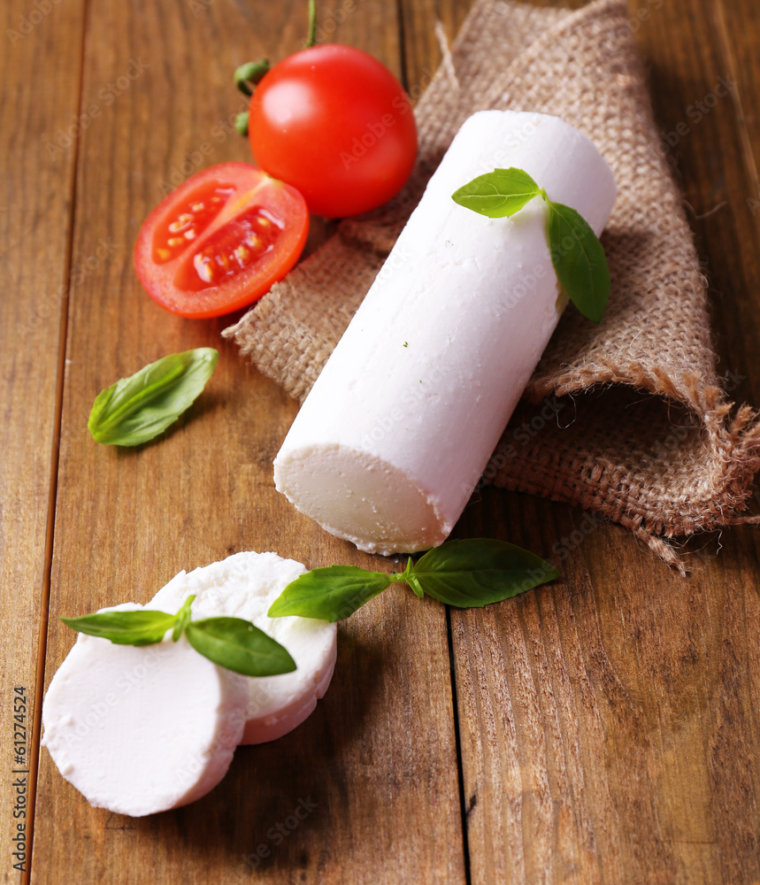Tasty bushe cheese with basil and tomato, on wooden table