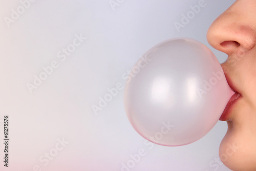 Person doing bubble with chewing gum on bright background