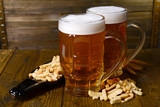 Glasses of beer with snack on table on wooden background