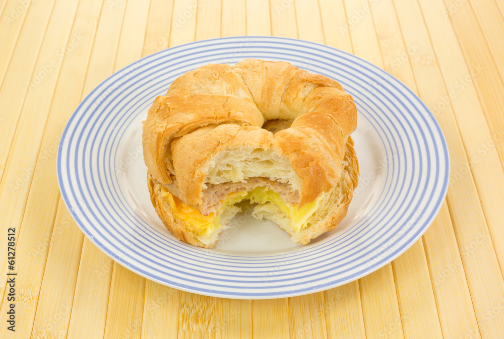 Bitten sausage egg and cheese croissant breakfast sandwich