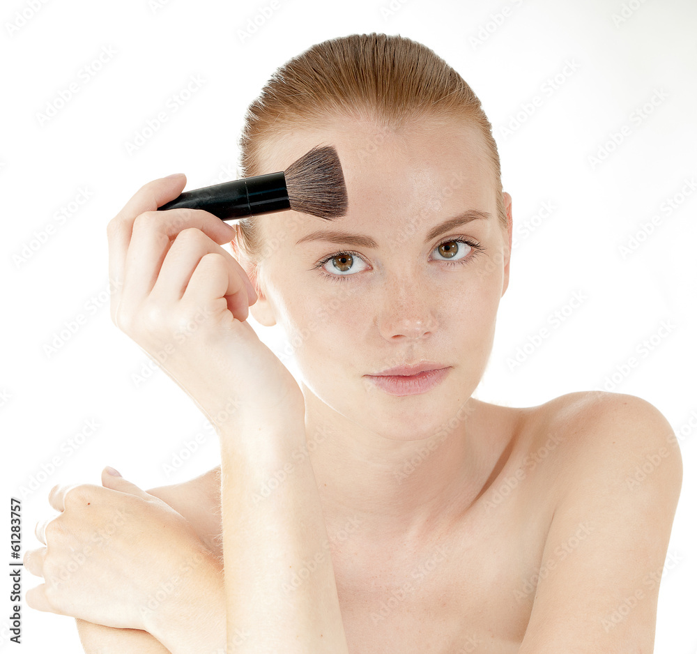 Young beautiful girl applying makeup by brush on her face. Young beautiful girl applying makeup by brush on her face.