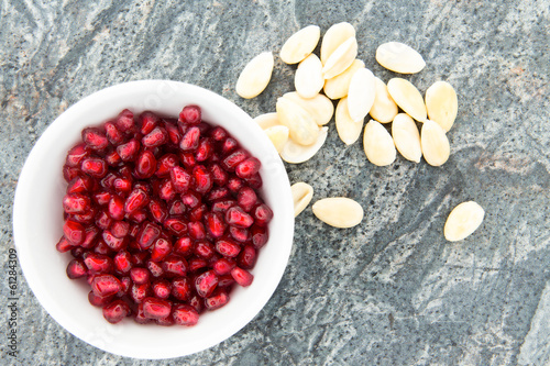 Seeds of fresh pomegranate, next to peeled almonds photo