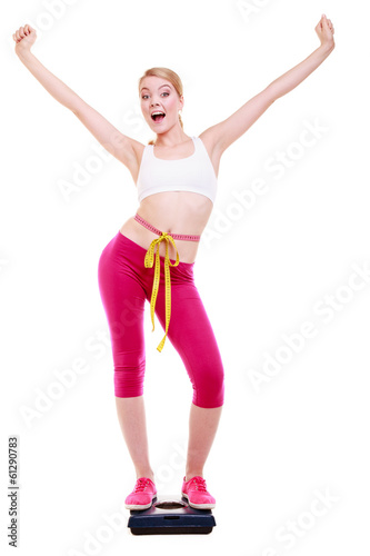 Woman with measure tape on scale celebrating weightloss