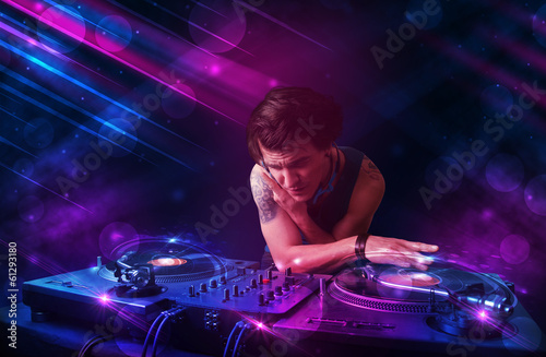 Young DJ playing on turntables with color light effects © ra2 studio