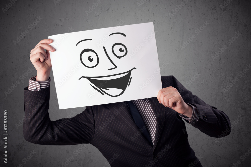 Businessman holding a cardboard with smiley face on it in front Businessman holding a cardboard with smiley face on it in front