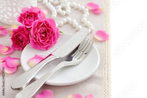 Romantic table setting with pink roses on a linen napkin