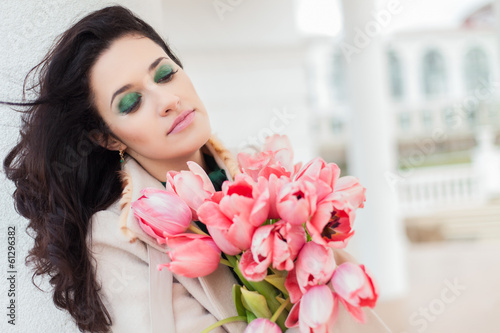 Beautiful young brunette woman with pink tulips in her hand