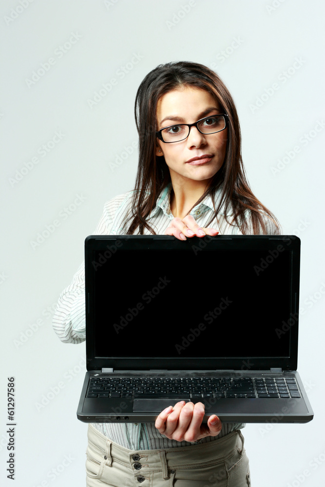 Young beautiful woman showing laptop on gray background Young beautiful woman showing laptop on gray background