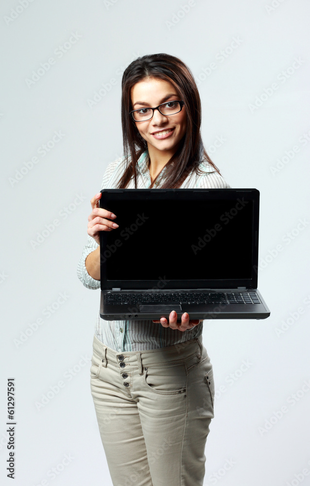 Young happy woman showing laptop on gray background Young happy woman showing laptop on gray background