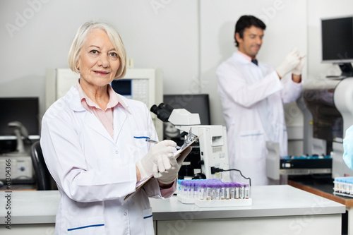 Female Scientist Writing On Clipboard In Laboratory