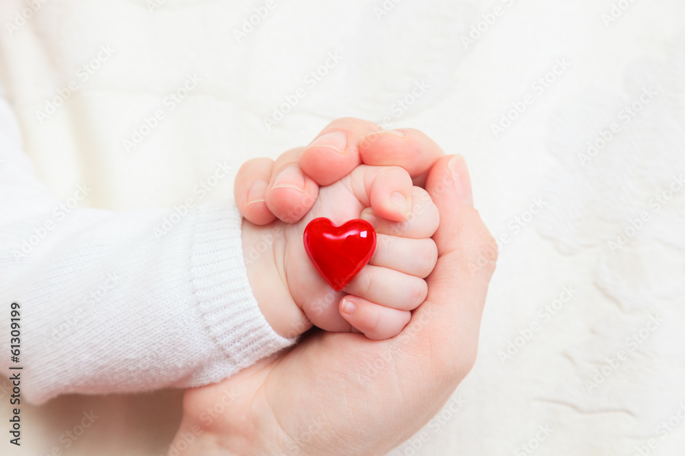 hands of mother and baby holding heart
