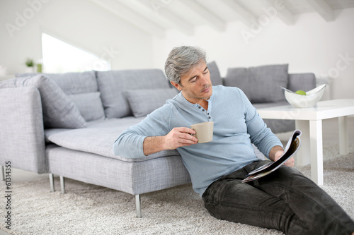 Senior relaxing at home and reading magazine