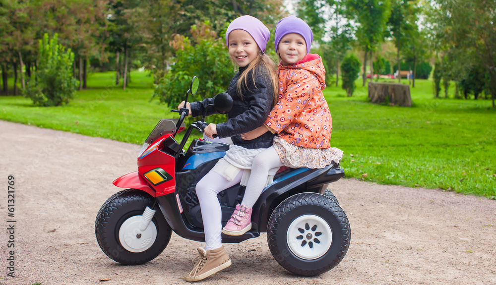 Portrait of adorable little girls ride a motorbike in green park Portrait of adorable little girls ride a motorbike in green park