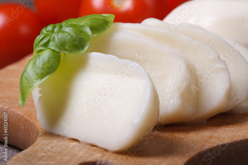 sliced ​​mozzarella cheese with basil on kitchen board