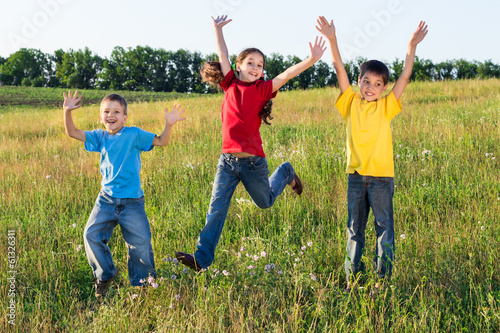 Jumping kids on green field