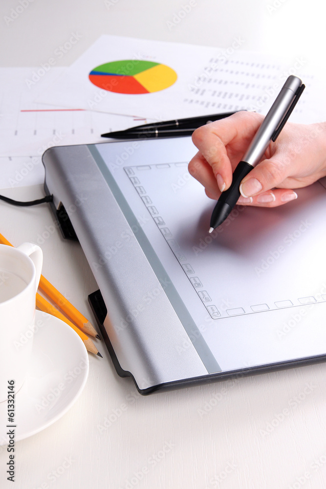 Female hand using graphics tablet on table close up Female hand using graphics tablet on table close up