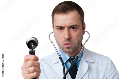 Serious male doctor holds stethoscope in hand on white backgroun