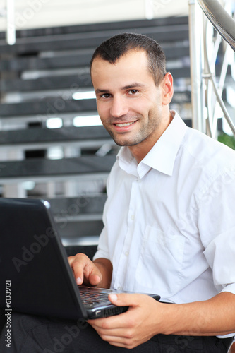 Businessman sitting on stairs and using laptop pc. 