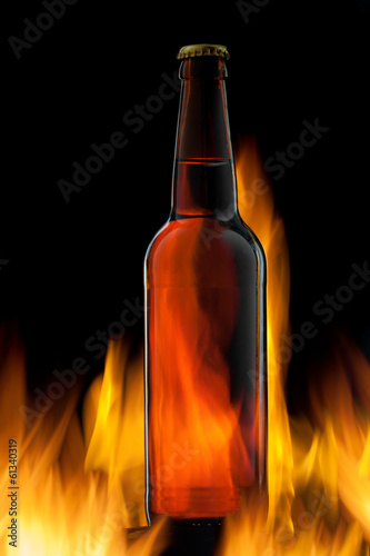 Beer bottle in fire on black