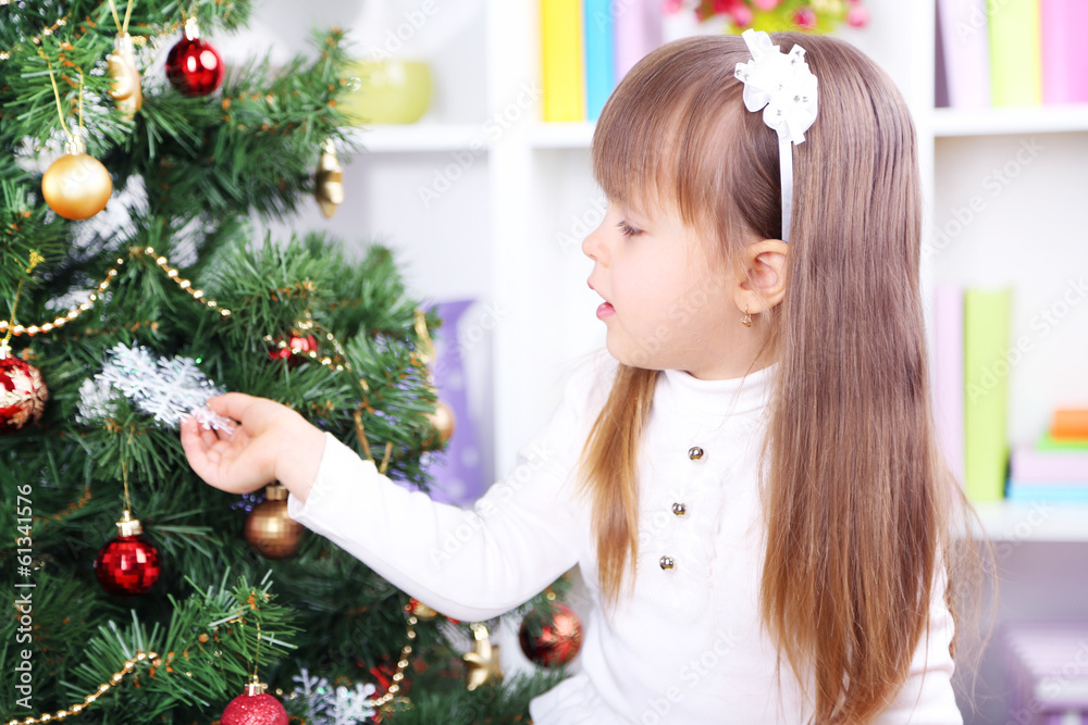 Little girl near Christmas tree in room