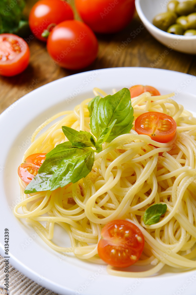 Delicious spaghetti with tomatoes on plate on table close-up Delicious spaghetti with tomatoes on plate on table close-up