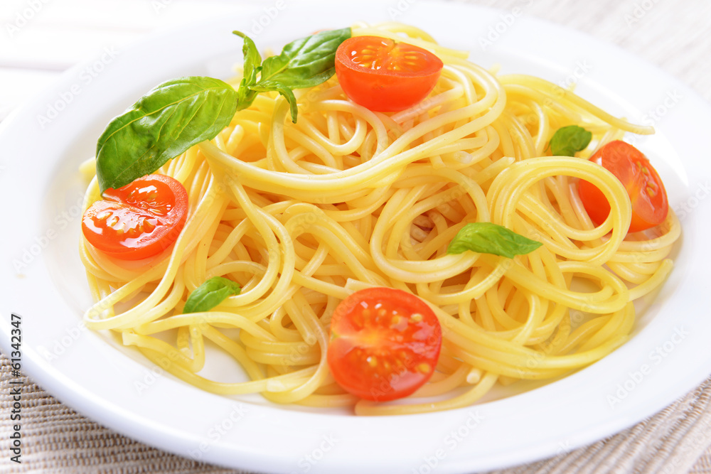 Delicious spaghetti with tomatoes on plate on table close-up Delicious spaghetti with tomatoes on plate on table close-up