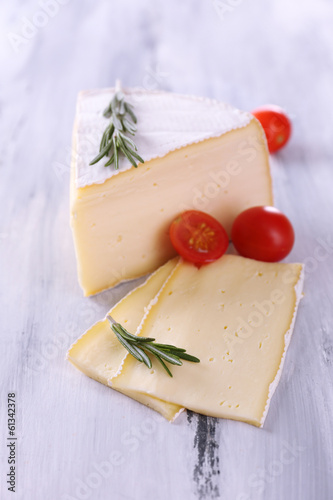 Tasty Camembert cheese with tomato and rosemary, on wooden