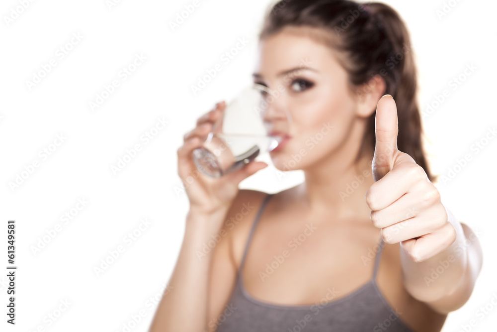 beautiful woman drinks water from a glass and showing thumbs up beautiful woman drinks water from a glass and showing thumbs up