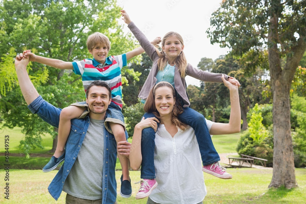 Parents carrying kids on shoulders at park