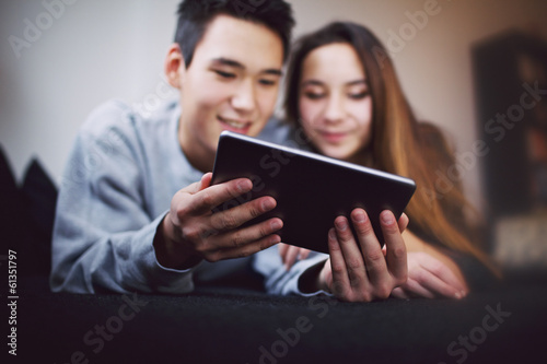 Teenage couple using tablet PC at home