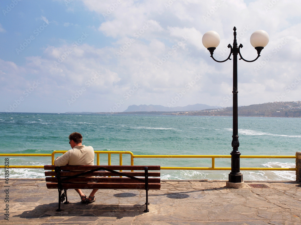 Obraz premium man sitting on a bench on the waterfront